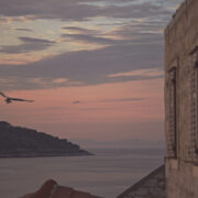 A pink and lavender Adriatic dusk seen from a stone window on the island of Vis, Croatia, with two gulls in flight and a distant fishing boat — limited edition fine art photograph by Tanja, My Empirical Life.